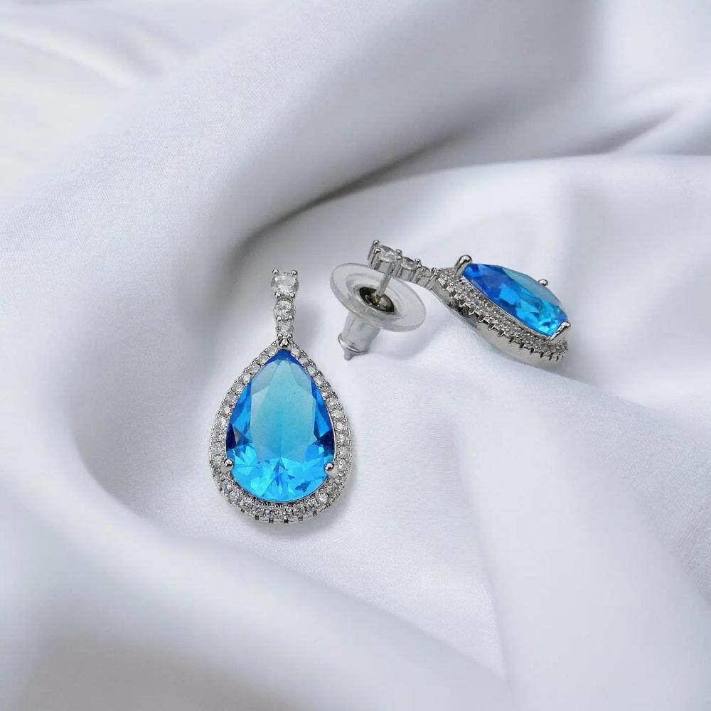 
                      
                        Zilverkleurige oorbellen met peervormige blauwe zirkonia's - Victoria Valenza
                      
                    