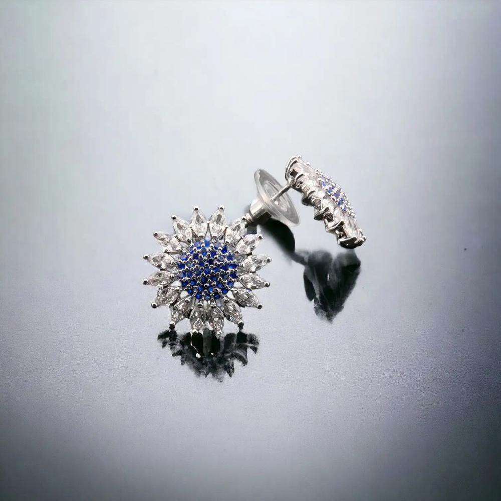 
                      
                        Zilverkleurige bloem oorknoppen met blauwe en witte zirkonia's - Victoria Valenza
                      
                    