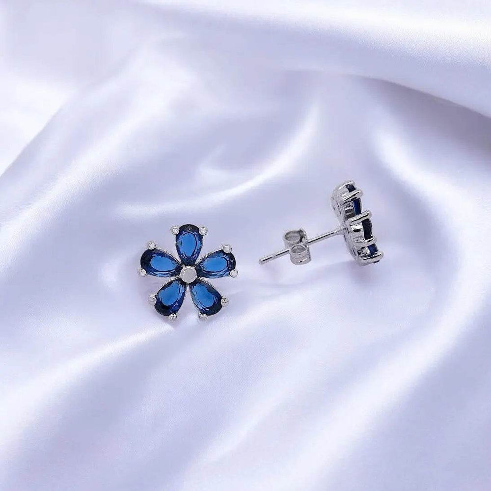 
                      
                        Zilverkleurige bloem oorbellen met donkerblauw zirkonia stenen - Victoria Valenza
                      
                    
