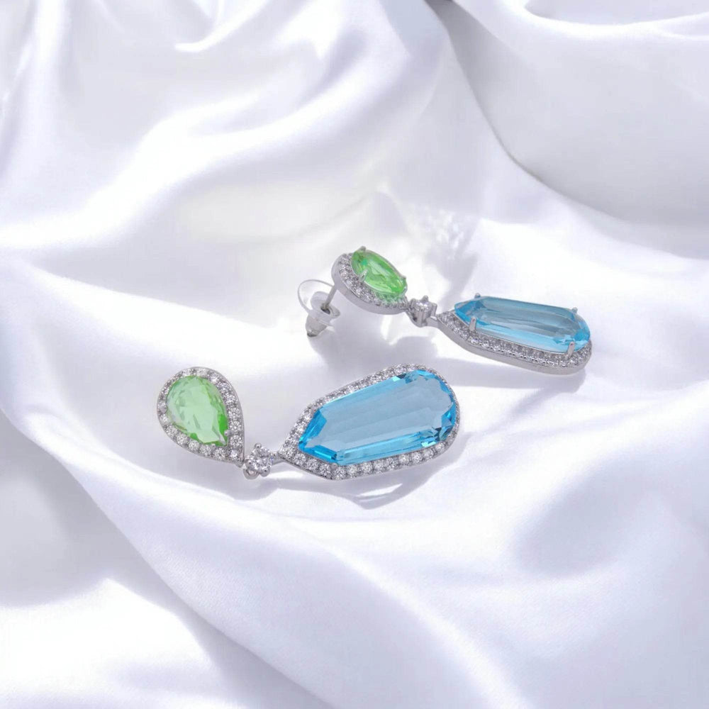 
                      
                        Zilverkleurige fantasie oorbellen met groene en blauwe zirkonia stenen - Victoria Valenza
                      
                    