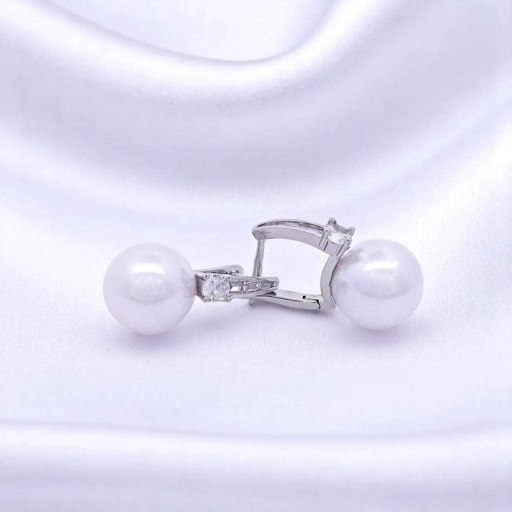 
                      
                        Zilverkleurige oorbellen met parels 14mm en zirkonia stenen.  Victoria Valenza
                      
                    