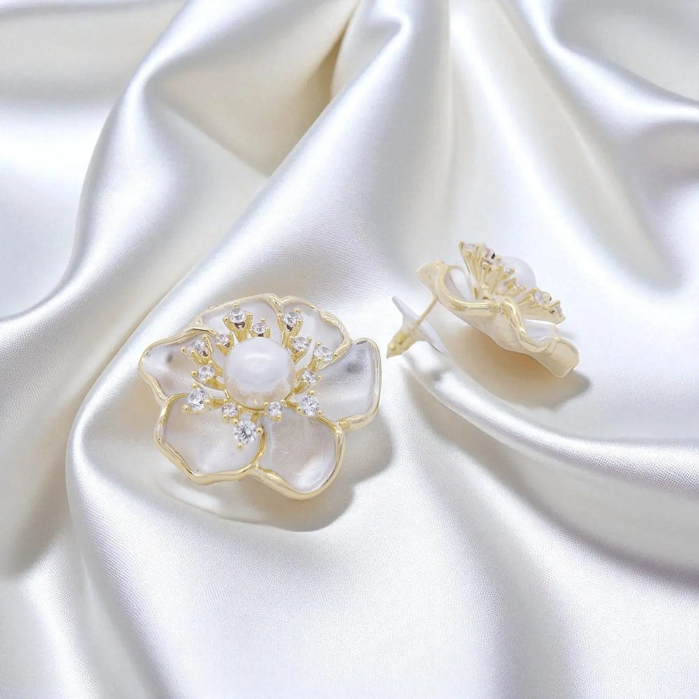 
                      
                        Goudkleurige sakura bloem oorbellen met parels, zirconia stenen en emaille  Victoria Valenza
                      
                    