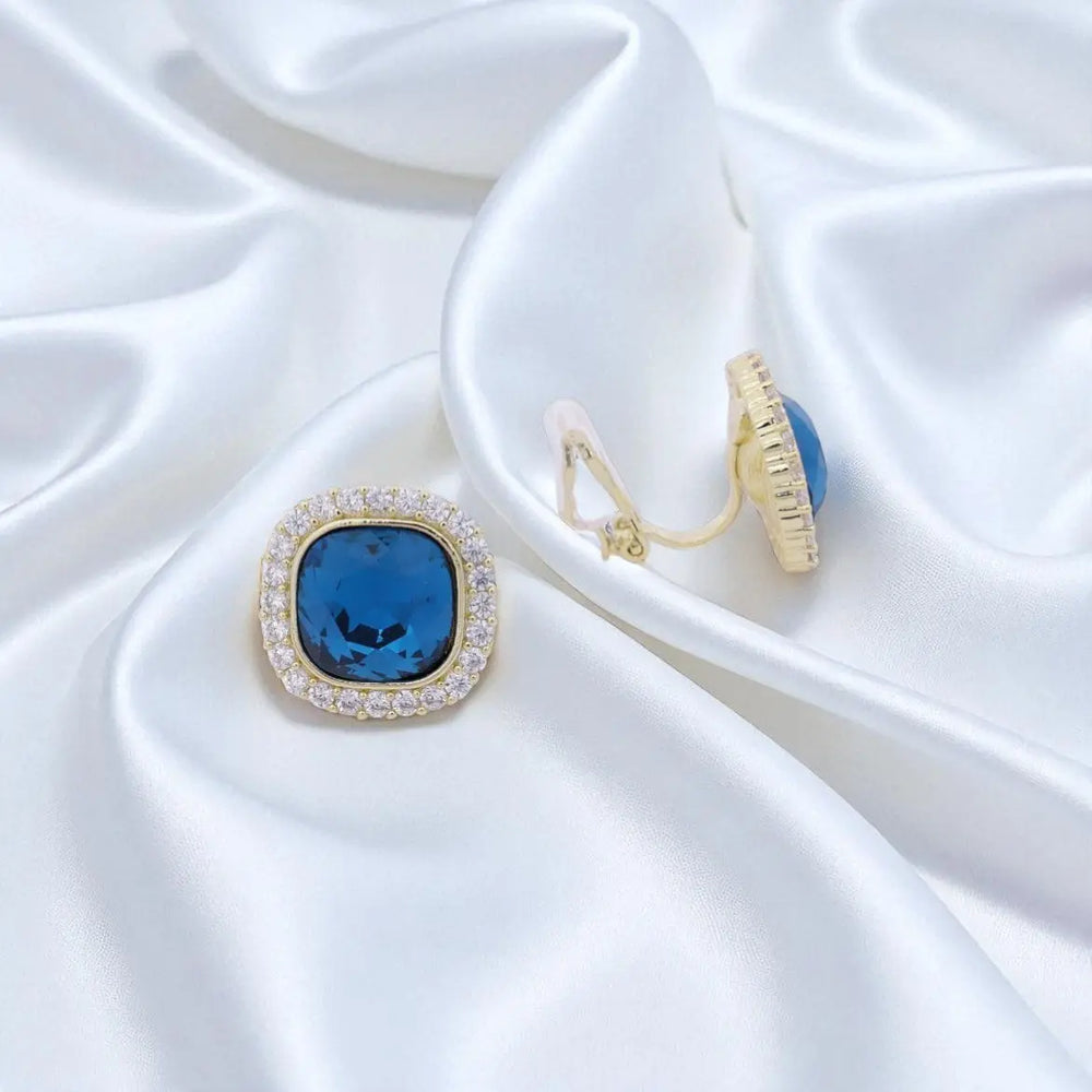 
                      
                        Goudkleurige entourage clip oorbellen met blauwe en witte zirkonia stenen  Victoria Valenza
                      
                    