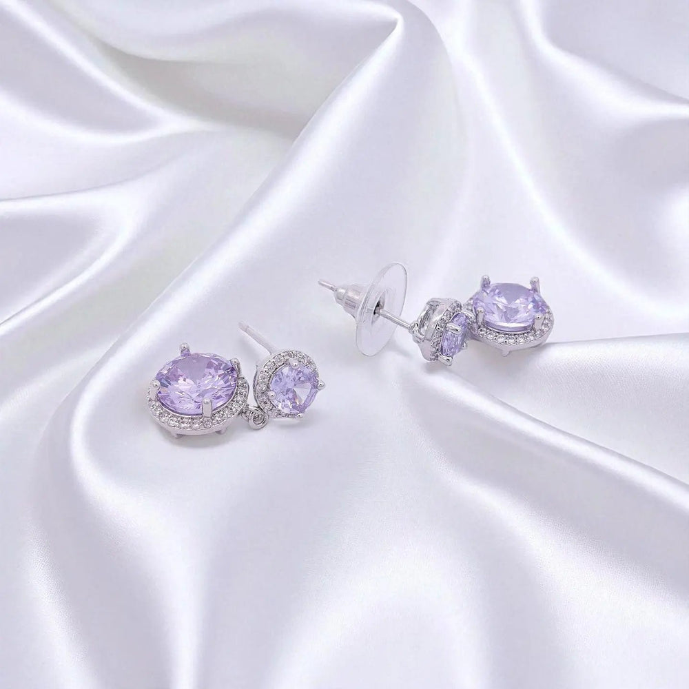 
                      
                        Zilverkleurige dubbel entourage oorbellen met paarse zirkonia stenen.  Victoria Valenza
                      
                    