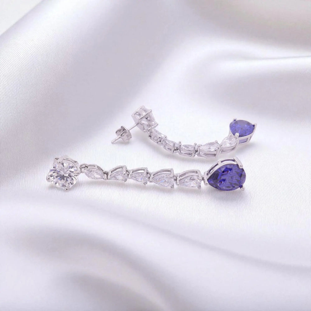 
                      
                        Zilveren dangle oorbellen met tanzaniet kleur zirkonia stenen  Victoria Valenza
                      
                    