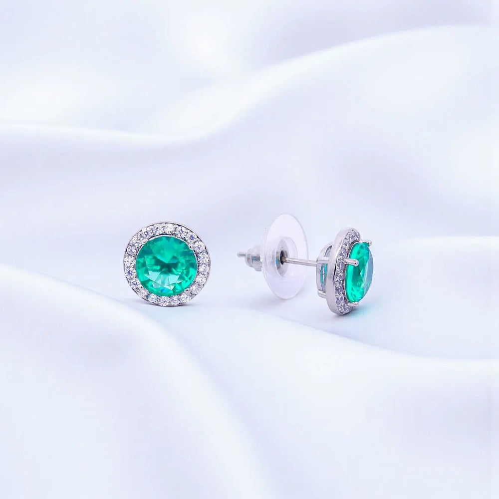 
                      
                        Zilverkleurige ronde turquoise entourage oorbellen met zirkonia stenen  Victoria Valenza
                      
                    