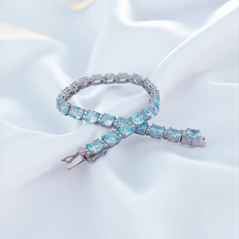 
                      
                        Zilveren armband met aquamarijnkleurige cushion zirkonia stenen  Victoria Valenza
                      
                    