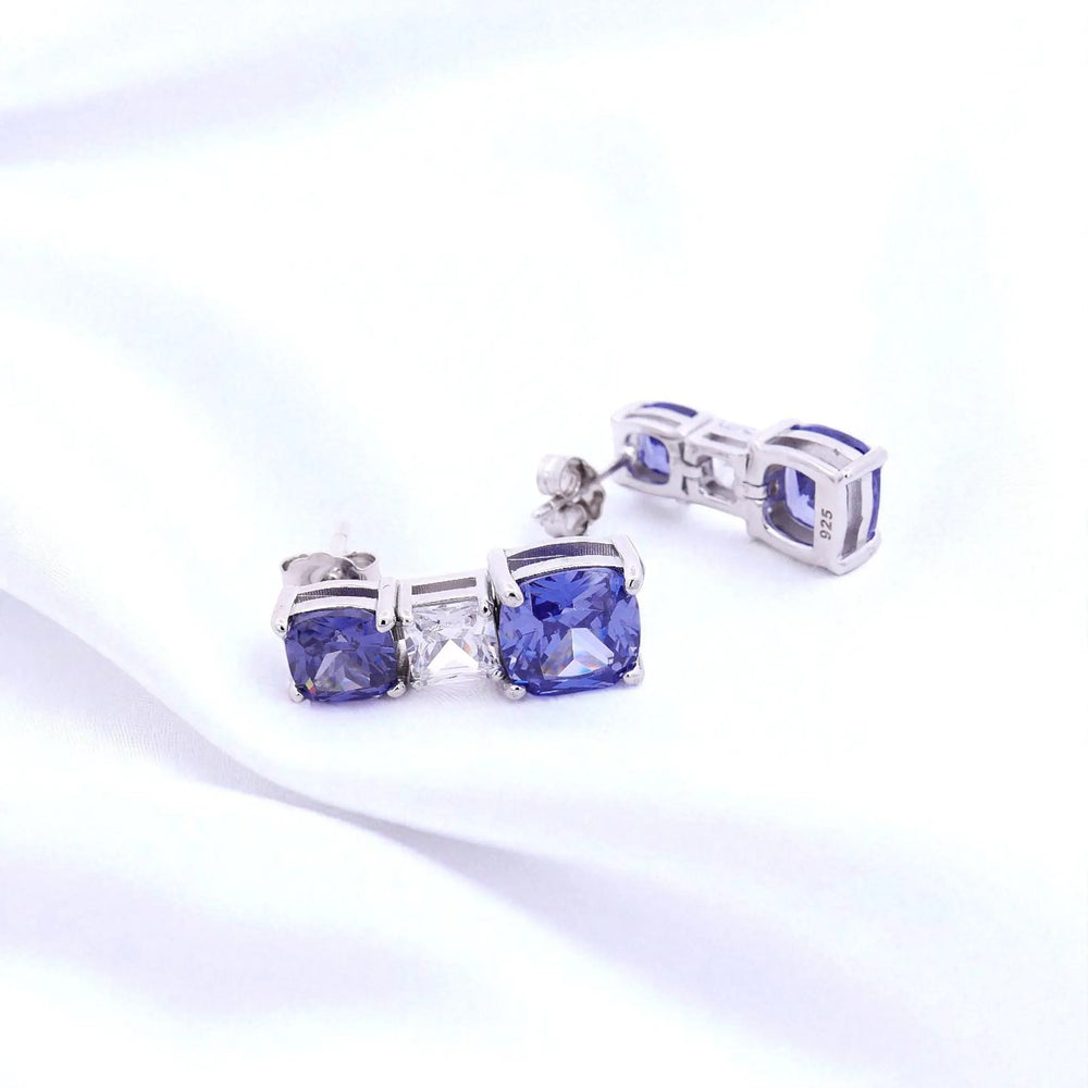 
                      
                        Zilveren oorbellen met tanzanietkleurige cushion zirkonia stenen  Victoria Valenza
                      
                    