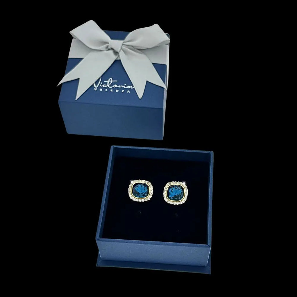 
                      
                        Goudkleurige entourage clip oorbellen met blauwe en witte zirkonia stenen  Victoria Valenza
                      
                    