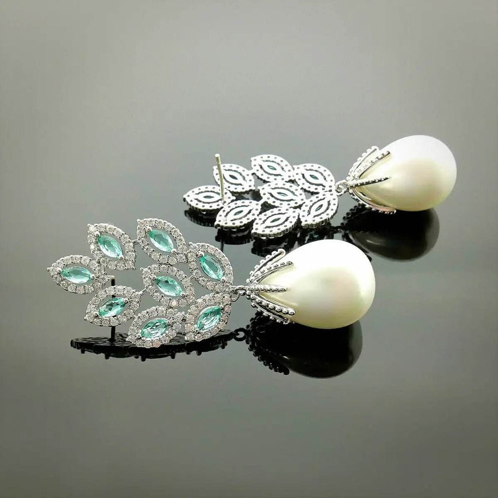 
                      
                        Zilverkleurige oorbellen met turquoise zirkonia's en parels - Victoria Valenza
                      
                    